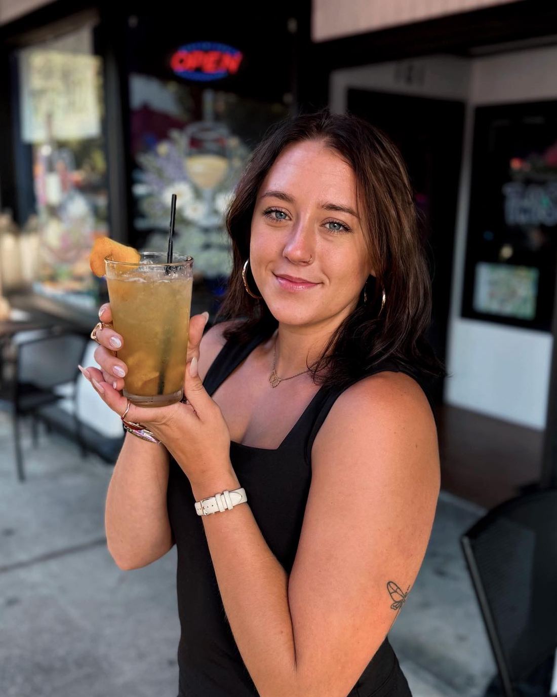 A guest with a cocktail at the door of Twysted Vyne on Courthouse Square, Inverness FL